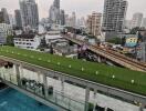 Modern urban building with rooftop greenery and pool overlooking cityscape