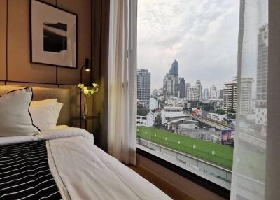 Bedroom with a large window overlooking a city skyline