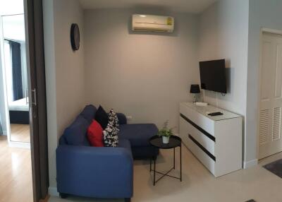 Modern living room with a blue sofa and wall-mounted TV