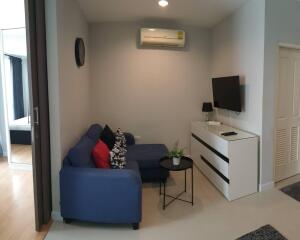 Modern living room with a blue sofa and wall-mounted TV