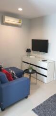 Modern living room with blue sofa, wall-mounted TV, and air conditioner