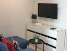 Modern living room with blue sofa, wall-mounted TV, and air conditioner