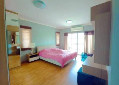 Spacious bedroom with large bed, wooden floor, and ample natural light