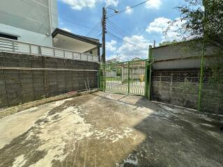 Outdoor area with concrete ground, fence, and neighboring buildings