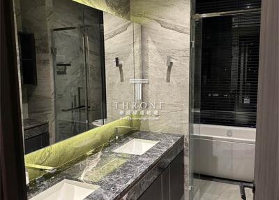 Modern bathroom with double sink, marble countertops, and glass-enclosed shower