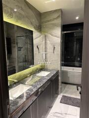 Modern bathroom with double sink, marble countertops, and glass-enclosed shower