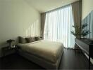 Cozy modern bedroom with large window and curtains, bed, side table with lamp, and TV