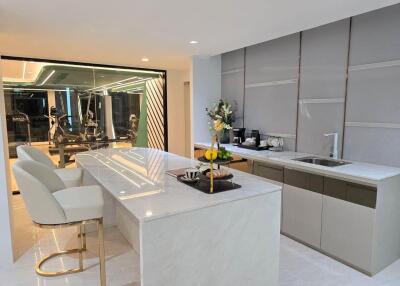 Modern kitchen with marble countertops and adjacent fitness area