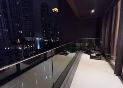 Night view of a spacious balcony with glass railing and cityscape background