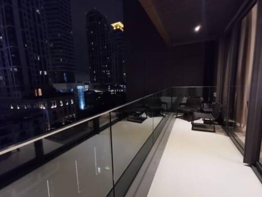 Night view of a spacious balcony with glass railing and cityscape background