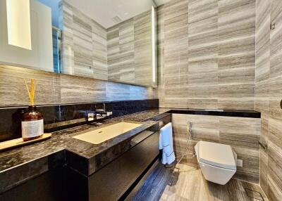 Modern bathroom with marble walls, large mirror, and stylish fixtures