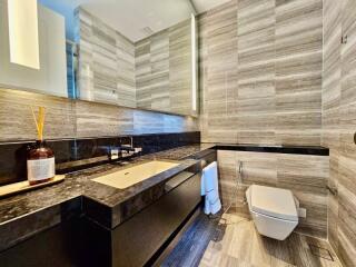 Modern bathroom with marble walls, large mirror, and stylish fixtures