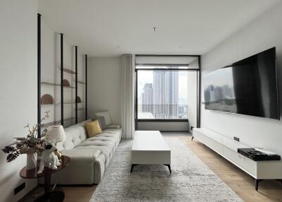 Modern living room with city view, large TV, and white furniture