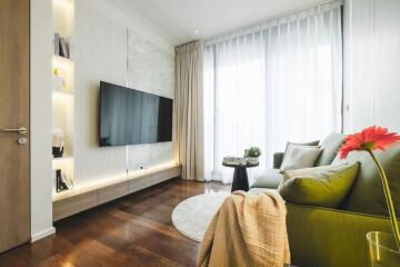 Modern living room with a large TV, green sofa, and wooden floors