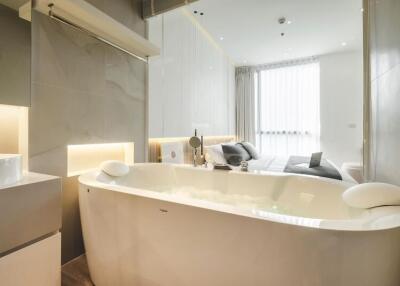 Modern bathroom with a free-standing bathtub and view into the bedroom
