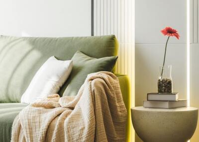 Cozy living room with green sofa, pillows, and a side table with a floral arrangement