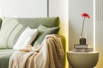 Cozy living room with green sofa, pillows, and a side table with a floral arrangement