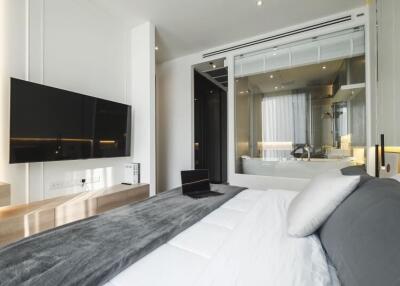 Modern bedroom with attached bathroom, wall-mounted TV, and workspace