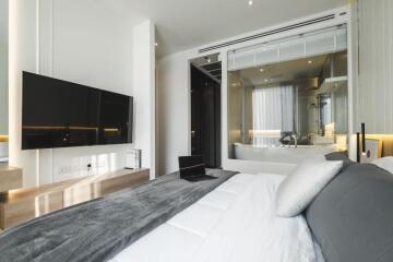 Modern bedroom with attached bathroom, wall-mounted TV, and workspace