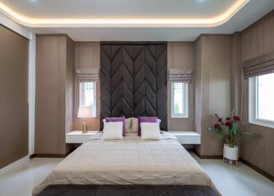 Modern bedroom with large bed, bedside tables, and windows