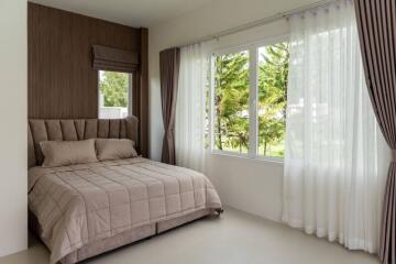 Spacious bedroom with large window and beige bedding