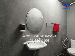 Simple bathroom with a round mirror, sink, and toilet