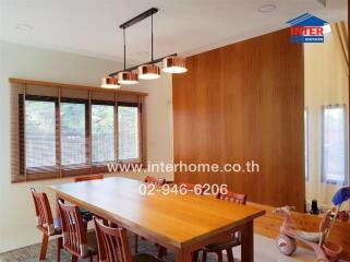 Dining room with wooden table, chairs, and a hanging light fixture