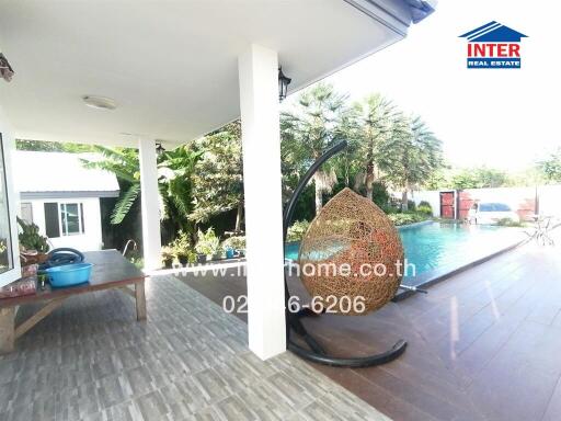 Covered outdoor patio with a swing chair next to a swimming pool