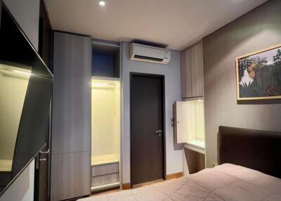 Modern bedroom with a TV, air conditioner, wardrobe, and artwork