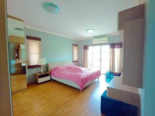 Spacious bedroom with wooden flooring, large window, and pink bedding