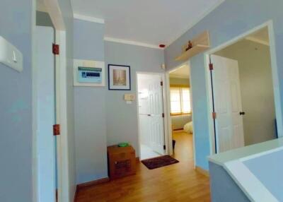 Bright hallway with wood flooring and several doorways leading to other rooms.