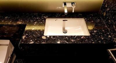 A stylish bathroom sink with a modern faucet and a black marble countertop.