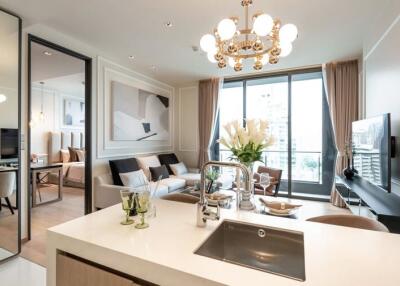 Modern open-plan living room with kitchen island, large window, and chandelier