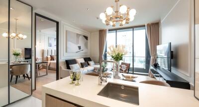 Modern open-plan living room with kitchen island, large window, and chandelier