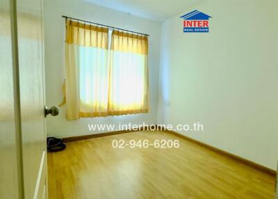Empty bedroom with wooden flooring and window with curtains