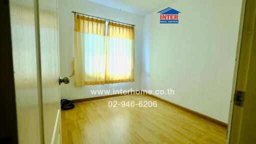 Empty bedroom with wooden flooring and window with curtains