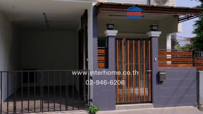 Exterior view of a townhouse with a gated entrance and a garage area