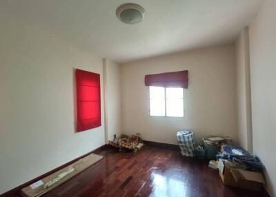 A bedroom with red curtains, wooden flooring, and simple furnishings