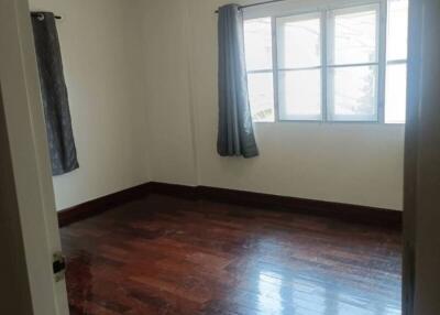 Empty bedroom with hardwood floors and a window with curtains