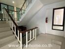 Staircase area with tiled floor and railing, adjacent to a glass-paneled wall and corridor