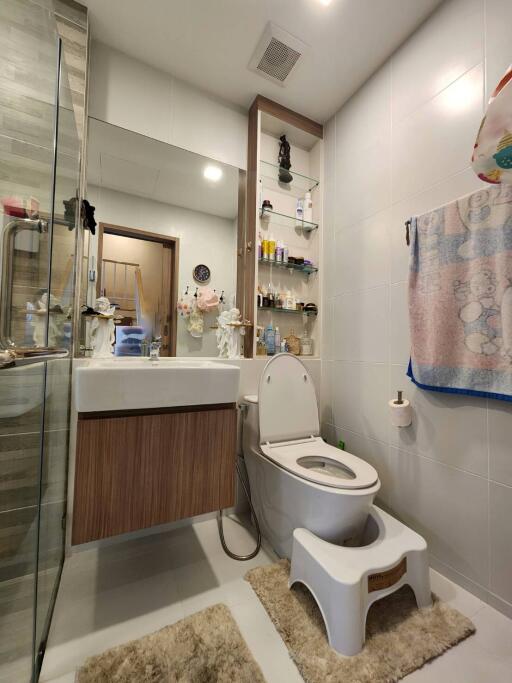 Modern bathroom with toilet, sink, and storage shelves