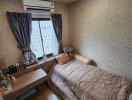 Small bedroom with a single bed, air conditioner, window with curtains, and a small desk.