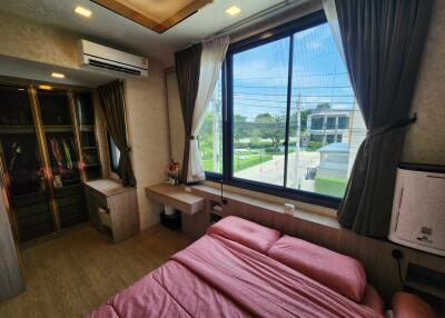 Bedroom with large window, bed with pink sheets, air conditioning, and wardrobe