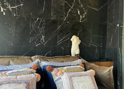 Stylish bedroom with decorative pillows and black marble accent wall