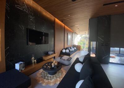Modern living room with wooden ceiling, black marble wall, and contemporary decor