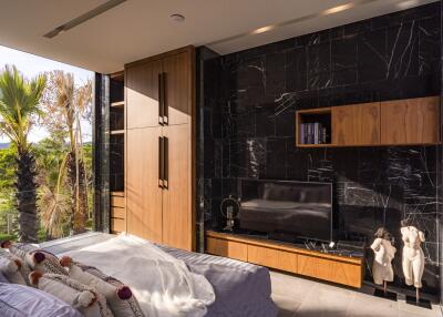 Modern bedroom with a TV, wooden cabinets, and wall-mounted shelves.