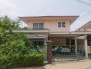 Front view of a two-story house with garden and carport