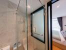 Modern bathroom with a glass-enclosed shower adjacent to a bedroom