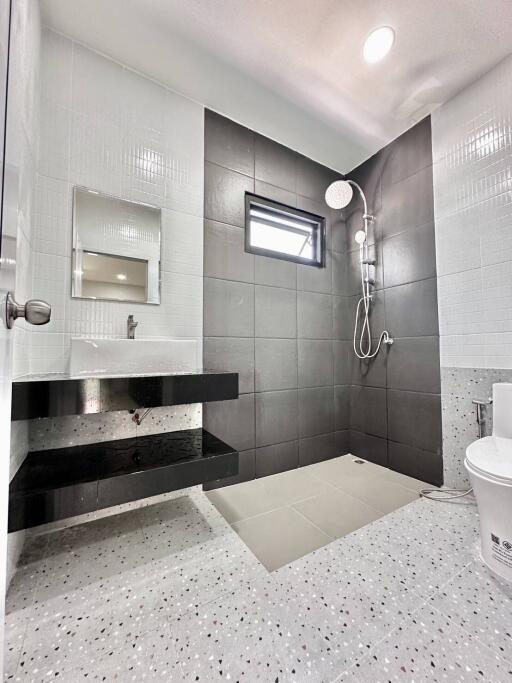 Modern bathroom with shower, sink, mirror, and toilet