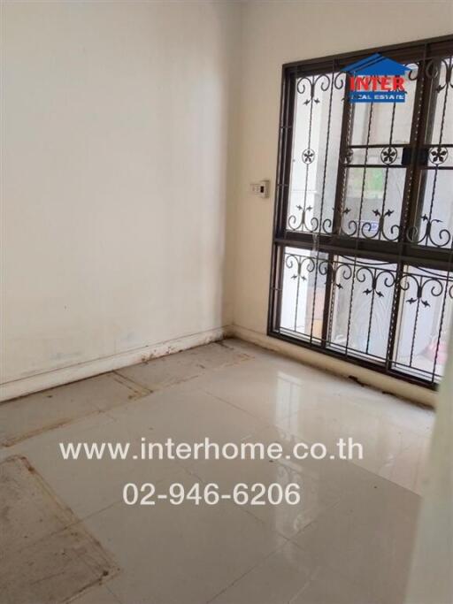 Empty room with tiled floor and window with metal bars